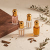 Four Oud Library perfume oil roll ons with gold caps on a cream surface with a wooden corner and eucalyptus