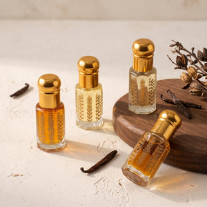 Four Oud Library perfume oil roll ons in gold topped bottles with dried vanilla pods on a cream surface